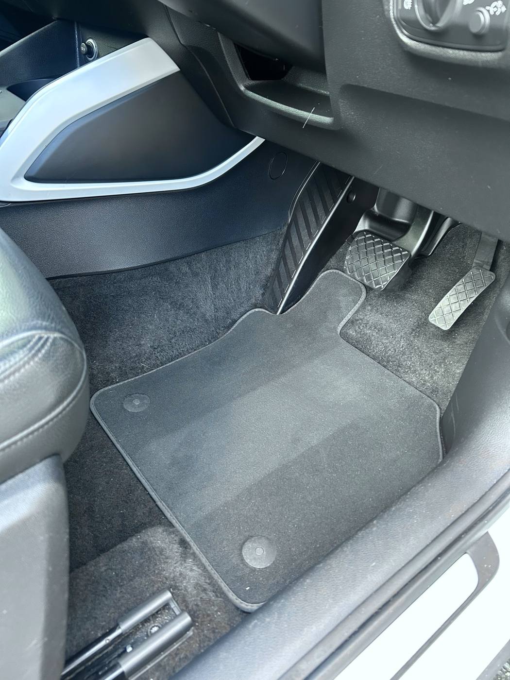 Driver footwell after detailing — vacuumed carpet and clean floor mat