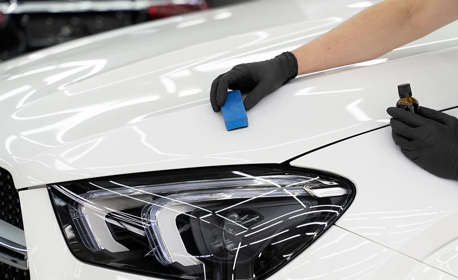 Ceramic coating being applied by hand to a white car bonnet