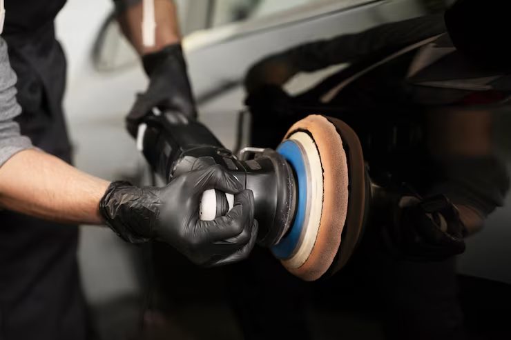Machine polisher with a foam pad correcting dark car paintwork
